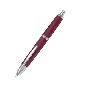 The Pilot Capless Wooden features an exclusive finish made from resin-impregnated toughened material derived from birch wood. With no cap, the 18 Karat rhodium plated gold nib retracts with a simple click. The first retractable fountain pen, the Capless, spent 6 years in development before its launch in 1963. The upper barrel of this precision instrument alone is made up of 18 components. Winner of the Japanese award for high technology in 1965, this legendary pen has gone on to conquer the world. One click deploys the nib, a second click retracts the nib, providing perfect leak-tightness, even without a cap. The ink never dries up, and the Capless is always ready for use. This is a product of unprecedented appeal and practicality. Product Number - 2073 - FC-2500RR-M-DR Red birch wood with rhodium trim Innovative push-button mechanism retracts and extends nib Sealed chamber protects nib and prevents leaks and drying 18k rhodium plated solid gold nib Fitted with ink converter for use with bottled ink Cartridge cover must be fitted over the cartridge during use Presented in premium Pilot Capless presentation box