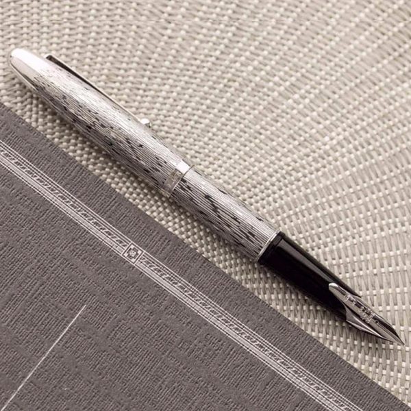 The Pilot Sterling Silver Tsumugi CT Fountain Pen is a handcrafted from genuine sterling silver. Each pen is engraved with an exquisite detailed design, a symbol chosen by Pilot to reflect an important facet of Japanese culture. “Tsumugi” has a pattern that is based on a piece of silk fabric. This fountain pen features a rhodium-plated 18k gold inlaid nib. A CON-40 converter is included with each pen, but they will also accept Pilot proprietary ink cartridges. The snap cap secures the pen when not in use and although it’s a bit heavy, it will post to make a nicely balanced pen when writing. The overall weight of a pen in the Sterling collection is around 34 grams, making it fairly comparable to the Pilot Metal Falcon. While tarnishing may be a concern given the material of the pen, the included polishing cloth will ensure easy, convenient cleaning of the pen body to keep away blemishes. The design on each pen will not hinder this cleaning either and allows for thorough, complete polishing. Model : FK5MSTUMINT Made From 925 Sterling Silver barrels and caps with Tsumugi Pattern Material: 925 Silver Snap Cap with Silver Plated trim Fountain pen comes with a Pilot CON-40 converter Nib : 18kt Gold Rhodium-plated inlaid nib Fountain pen is presented in a beautiful Pilot gift box. Brand Origin: Japan